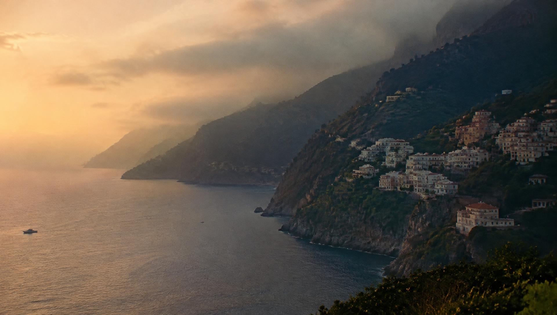 Coastline at dawn, mist over cliffside village